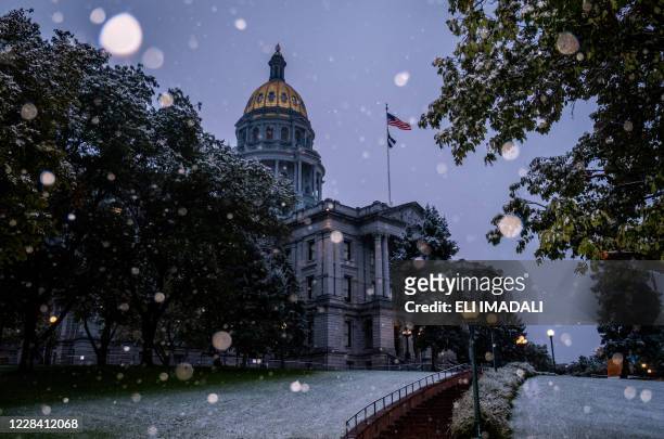 Snow falls outside the Colorado State Capitol building in Denver, Colorado on September 8, 2020. After a weekend of record-setting heat topping off...