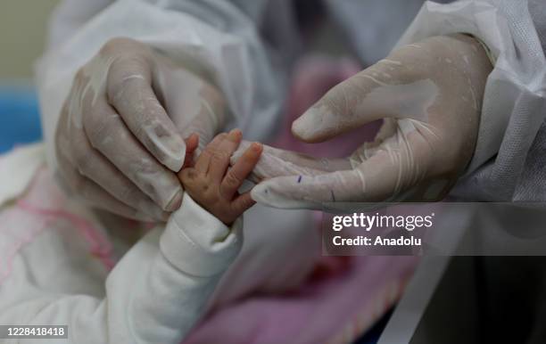 Baby's hand is seen as routine vaccination of babies are started after 20 days under the measures taken against the coronavirus in Deir al Balah,...