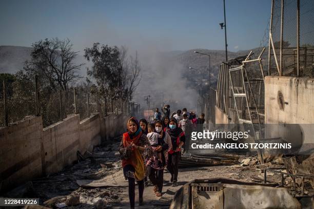 People walk in the burnt camp of Moria on the island of Lesbos after a major fire broke out, on September 9, 2020. - Thousands of asylum seekers on...