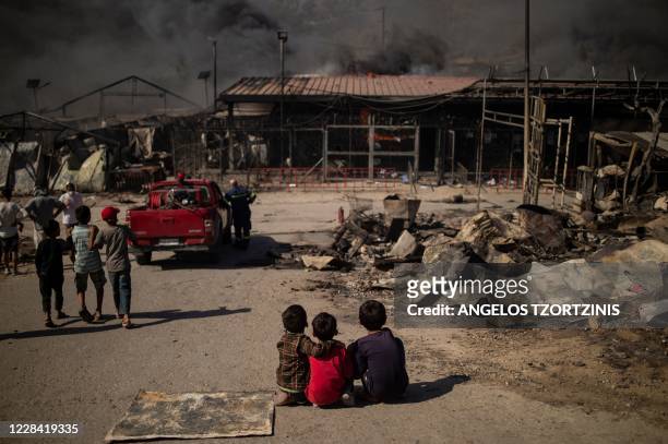 Children sit on the ground in the burnt camp of Moria on the island of Lesbos after a major fire broke out, on September 9, 2020. - Thousands of...