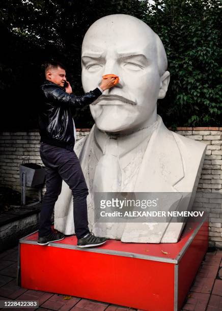 Staff member of a local branch of Russian Communist party washes a huge monument to Vladimir Lenin in front the party's local office in Novosibirsk...