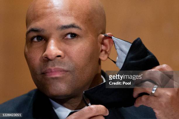 Surgeon General Jerome Adams takes off his face mask during a Senate Health, Education, Labor, and Pensions Committee hearing to discuss vaccines and...