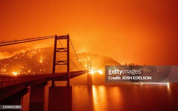 Boat motors by as the Bidwell Bar Bridge is surrounded by fire in Lake Oroville during the Bear fire in Oroville, California on September 9, 2020. -...