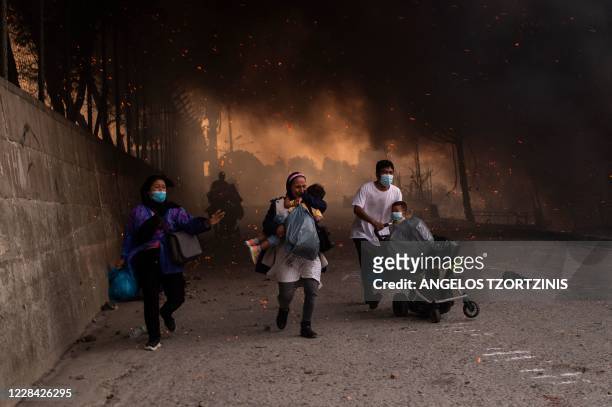 People with children flee flames major fire broke out in the Moria migrants camp on the Greek Aegean island of Lesbos, on September 9, 2020. -...