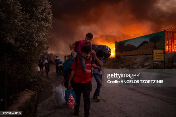 People with children flee flames after a major fire broke out in the Moria migrants camp on the Greek Aegean island of Lesbos, on September 9, 2020....