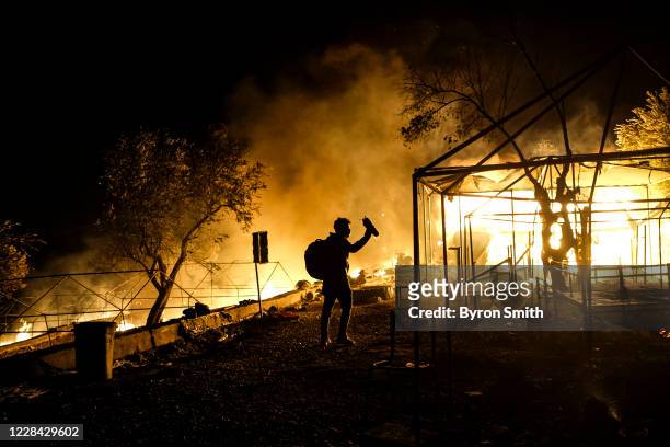An asylum-seeker retrieves his belongings from his burnt down tent as fires continue to rage for a second night in the Moria migrant camp on...