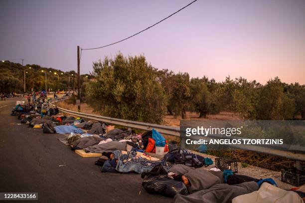 Migrants sleep on the ground after spending the night on the road near Mytilene, as a fire destroyed Greece's largest Moria refugee camp on the...