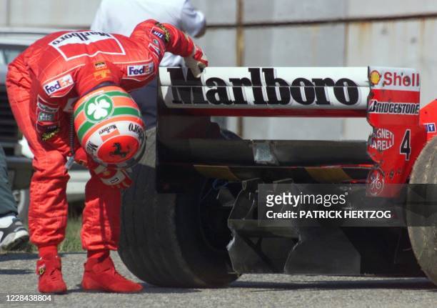 Northern Ireland's Ferrari driver Eddie Irvine looks at the back of his car after he lost control of it, 14 August 1999, on the Hungaroring racetrack...