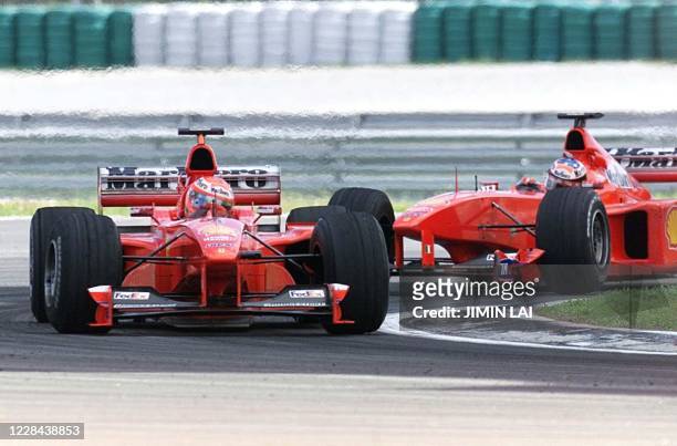 Ferrari team driver Eddie Irvine of Northern Ireland leads teammate Michael Schumacher of Germany 17 October 1999 as they take the last corner just...