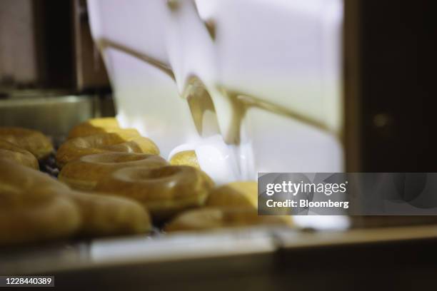 Donuts pass through a glaze waterfall inside a Krispy Kreme Doughnuts Inc. Store in the Times Square neighborhood of New York, U.S., on Thursday,...