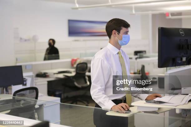 An employee wears a protective mask while working at a computer station at a JLL office in Dallas, Texas, U.S., on Wednesday, Sept. 9, 2020....