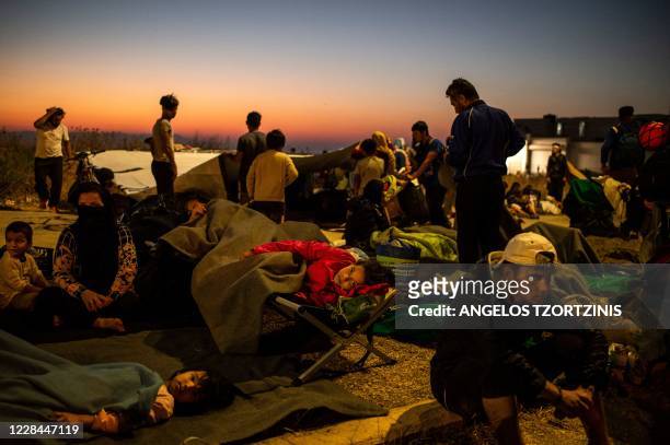 Migrants rest as they spend the night on the road near Mytilene, after a fire destroyed Greece's largest Moria refugee camp on the island of Lesbos,...