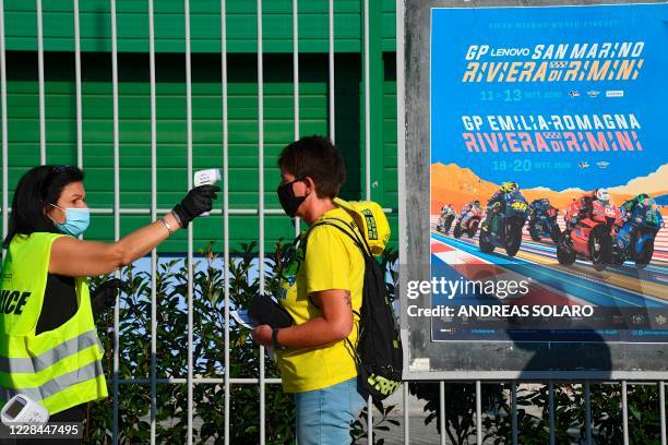 Staff member of Misano Circuit checks the body temperature of a visitor as a preventive measure against the spread of the Covid-19 coronavirus, at...