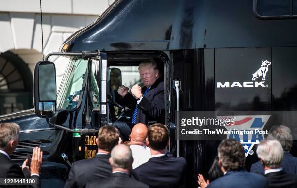 President Donald Trump jumps up in the cab of an 18 wheeler truck while meeting with truckers and CEOs regarding healthcare on the South Lawn of the...