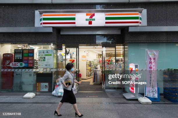 Woman wearing a face mask walks past a 7 Eleven convenience Market in Minato-Ku. Although Coronavirus Pandemic is still present, Japanese economy is...