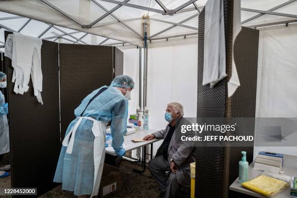 Medical staff with protective gear speaks with a man as he conducts tests for Covid-19, on September 11, 2020 in Venissieux, near Lyon, amid the...