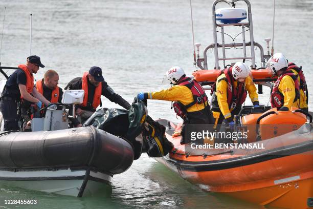 Members of the RNLI pass a deflated dinghie to member of the Boarder Force after migrants were picked up at sea whilst crossing the English Channel...