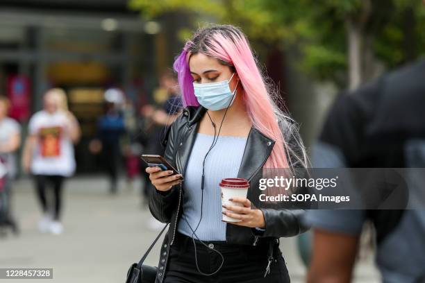 Woman wearing a face mask looks at her mobile phone.