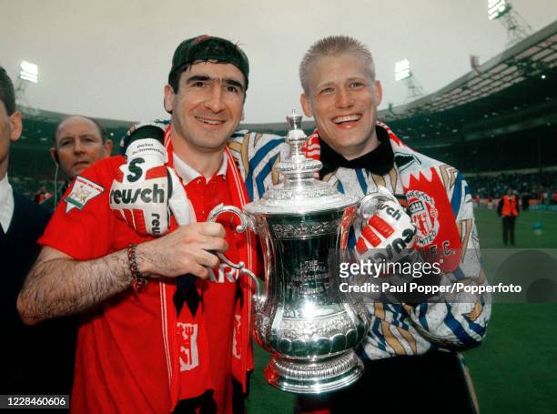 Manchester United goalkeeper Peter Schmeichel and teammate Eric Cantona celebrate with the trophy after the FA Cup Final between Chelsea and...