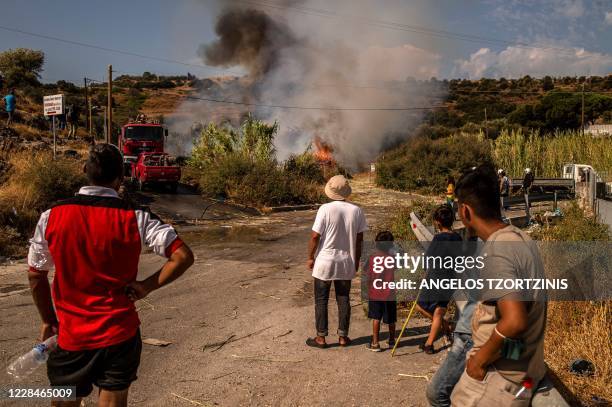 Refugees and migrants from the Moria camp look at a fire that broke out during a protest near Mytilene on the Greek island of Lesbos, on September 12...