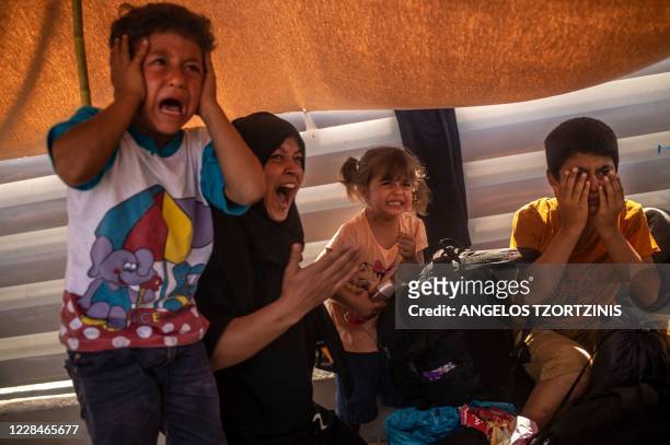 Migrant woman and children react after police threw tear gas during clashes near the city Mytilene on the Greek island of Lesbos, on September 12 a...