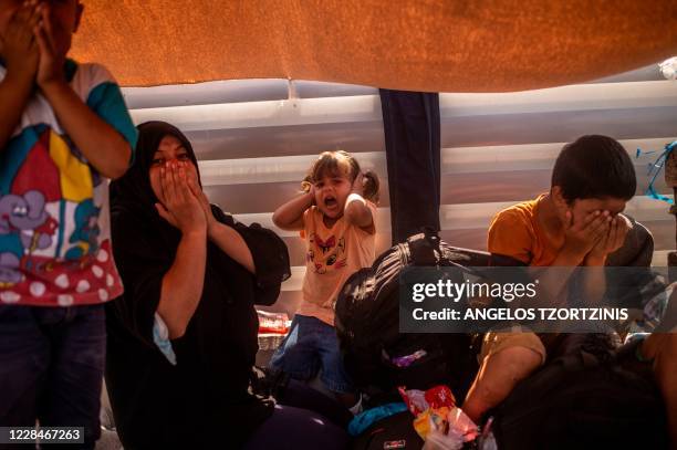 Migrant woman and children react after police threw tear gas during clashes near the city Mytilene on the Greek island of Lesbos, on September 12 a...