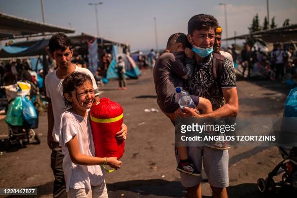 Refugees and migrants react after police threw tear gas during clashes near the city of Mytilene on the Greek island of Lesbos, on September 12 a few...
