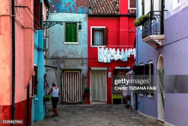 Man walks in a street of Burano, the most colorful island in the Venice lagoon, on September 11, 2020.