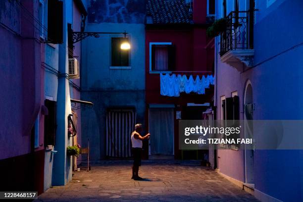 Man stands at dusk in a Burano street, the most colorful island in the Venice lagoon, on September 11, 2020.