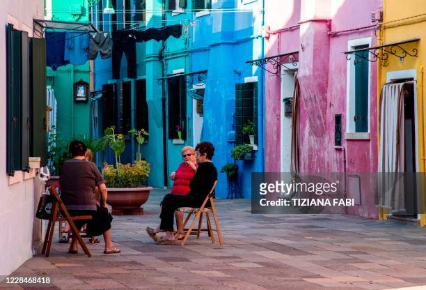 Elderly women sit together in a street of Burano, the most colorful island in the Venice lagoon, on September 11, 2020.