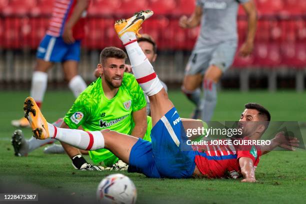 Athletic Bilbao's Spanish goalkeeper Unai Simon vies with Granada's French midfieder Maxime Gonalons during the Spanish league football match Granada...