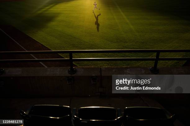 Right fielder Charlie Blackmon of the Colorado Rockies jogs off the field past empty seats as the sun sets during the second inning against the Los...
