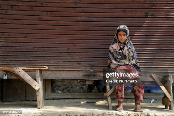 Muslim girl sits on a bench outside a closed shop in Khudgoo Mungluu area of sopore, district baramulla Jammu and Kashmir, India on 13 September...