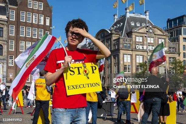 Man holds a sign and a Iranian flag during a demonstration on the Dam Square in Amsterdam, the Netherlands, on September 13 against Iranian wrestler...