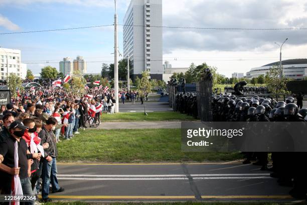Opposition supporters stand in front of law enforcement officers blocking the street during a rally to protest against the presidential election...
