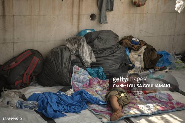 Child sleeps along the roadside where thousands are living with out shelter and exposed to the elements following the burning down of their camp,...