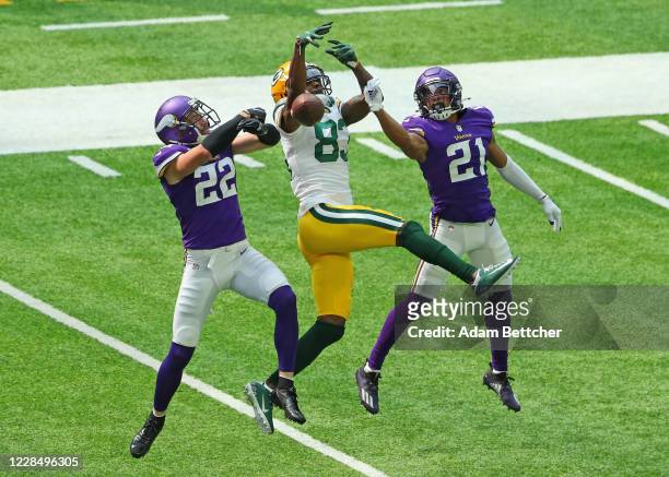 Marquez Valdes-Scantling of the Green Bay Packers attempts to catch a pass against Mike Hughes and Harrison Smith of the Minnesota Vikings in the...