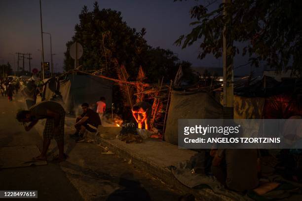 Migrant cooks over a fire near the Kara Tepe camp on the island of Lesbos on September 13, 2020. - Over 11,000 people -- including some 4,000...