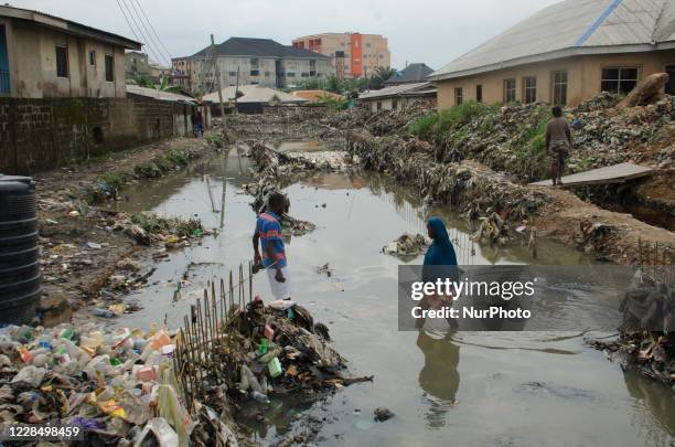 People walk through a flooded canal at Oyebanjo Solarin Street in Ketu, Lagos which washed away a two yet to be identified children, after a heavy...