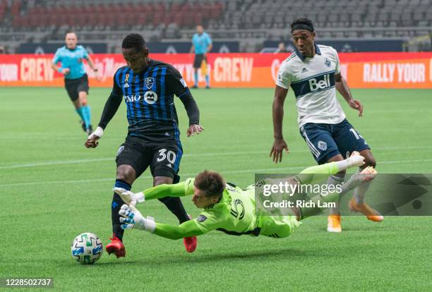 Goalkeeper Thomas Hasal of the Vancouver Whitecaps dives at the ball and knocks down Romell Quioto of the Montreal Impact as Derek Cornelius of the...