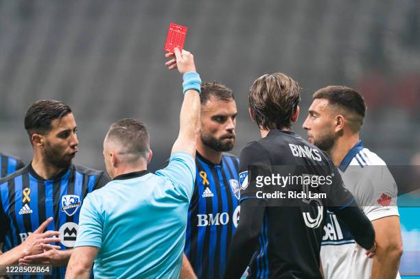 Referee Pierre-Luc Lauziere issues a red card to Lucas Cavallini of the Vancouver Whitecaps as a group of Montreal Impact players gather during MLS...
