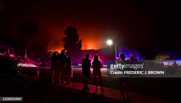 People watch as the Bobcat Fire burns on hillsides behind homes in Arcadia, California on September 13, 2020 prompting mandatory evacuations for...