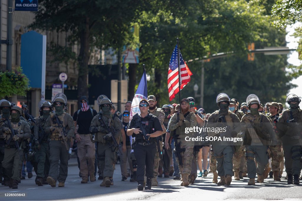 Armed gun rights protesters march down Broad Street.