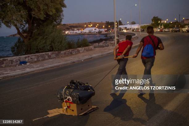 Migrants pull their belongings along a road near the temporary refugee camp on the Greek island of Lesbos on September 14, 2020. - Over 11,000 people...