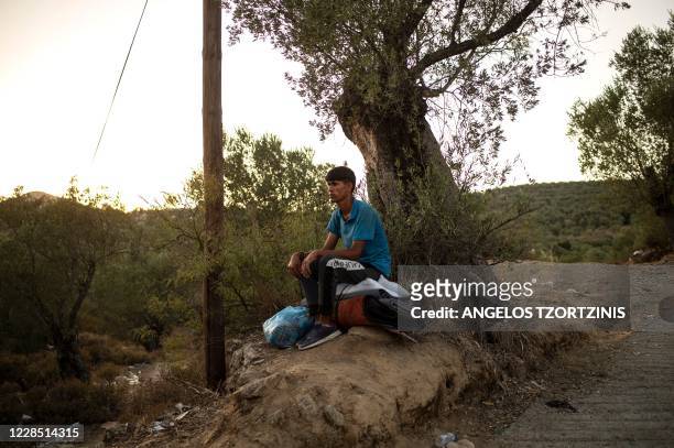 Migrant sits on his belongings near the burnt Moria refugee camp on the Greek island of Lesbos on September 14, 2020. - Over 11,000 people --...