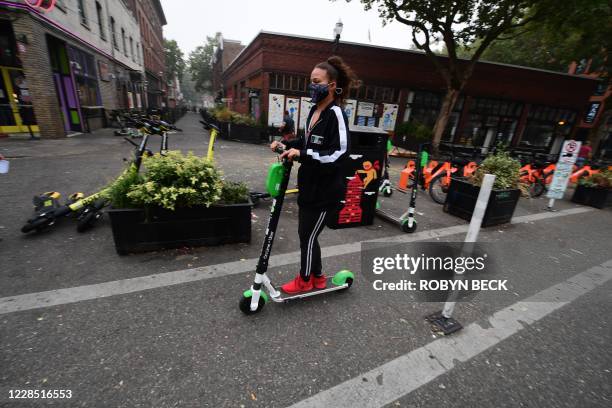 Woman wears a mask as she rides a scooter in downtown Portland, Oregon where air quality due to smoke from wildfires was measured to be amongst the...