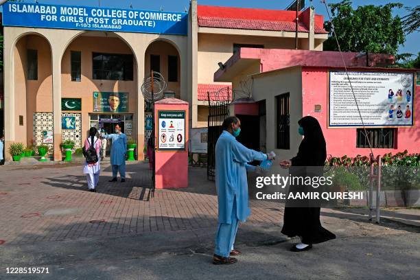 Student wearing a facemask gets her hands sanitized upon her arrival at the Islamabad Model College of Commerce for Girls in Islamabad on September...