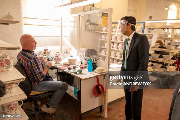 Britain's Chancellor of the Exchequer Rishi Sunak, wearing a face visor due to the COVID-19 pandemic, talks with employees during his visit to the...