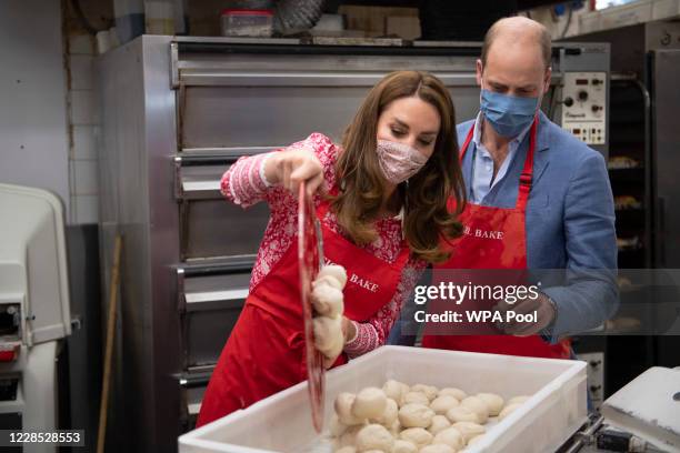Prince William, Duke of Cambridge and Catherine, Duchess of Cambridge pour a tray of dough into a container as they help make beigels during a visit...