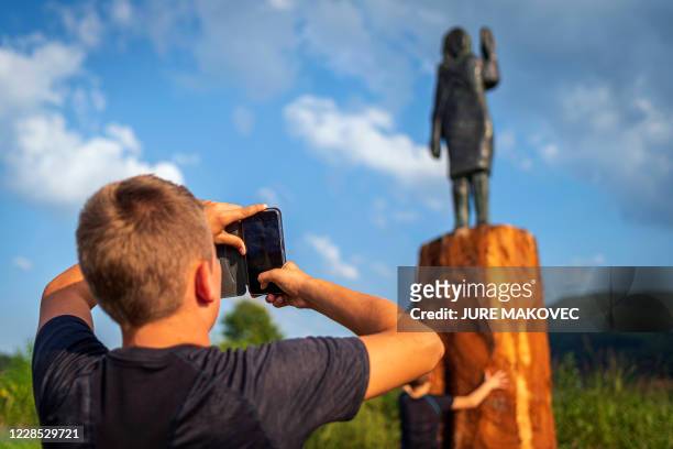 Boy takes a picture with his mobile phone of a bronze replica depicting US First Lady Melania Trump, made by US artist Brad Downey, after its...